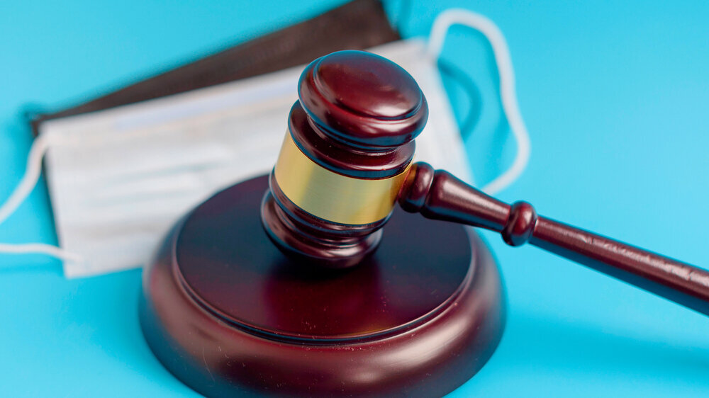 brown gavel and medical protective masks on a blue background Corona Gerichtsurteil