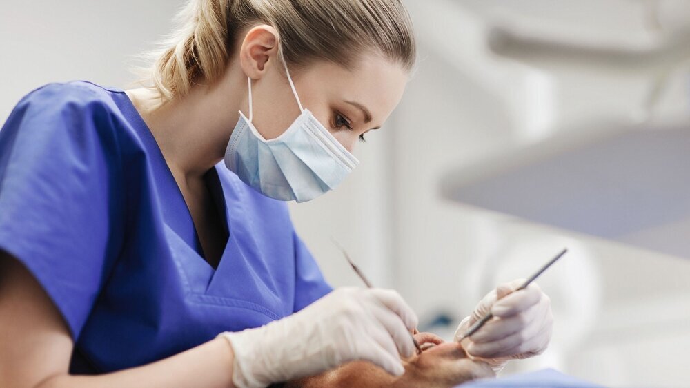 female dentist checking up male patient teeth Zahnärztin