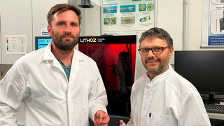 Doktorand Christian Polley (links) und Professor Hermann Seitz (rechts) vor einem 3D-Drucker