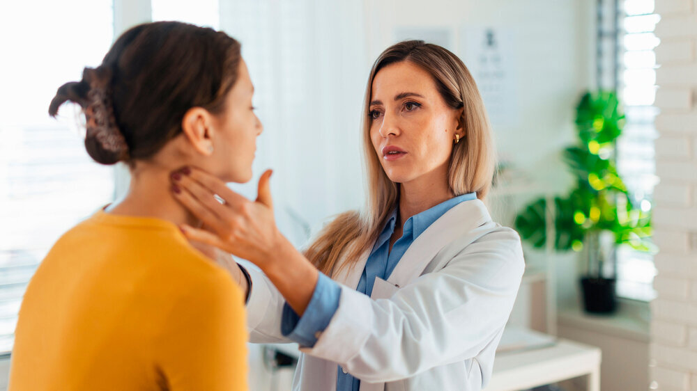 Doctor examining lymp nodes on neck of the teenage girl. Concept of preventive health care for adolescents.