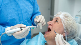 dentist surgeon installing an implant to an elderly woman. Prosthetic dentistry, false teeth