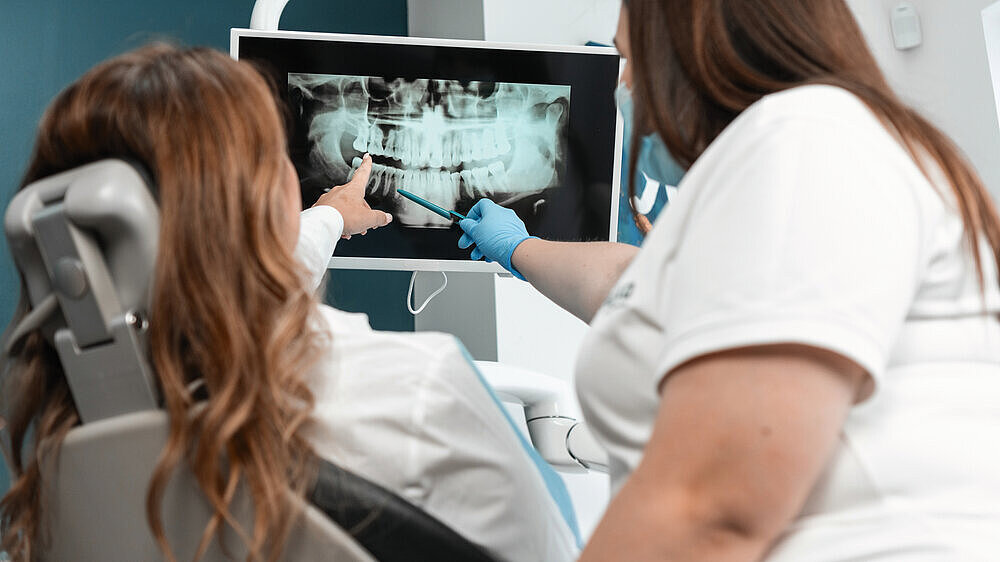 The dentist shows the patient a panoramic X-ray on the monitor, carefully explaining all the details and features of her dental condition. A dentist with great professionalism shows the patient a panoramic X-ray on the monitor and clearly explains her ora The dentist shows the patient a panoramic X-ray on the monitor, carefully explaining all the details and features of her dental condition. A dentist with great professionalism shows the patient a panoramic X-ray on the monitor and clearly explains her oral health. High quality photo