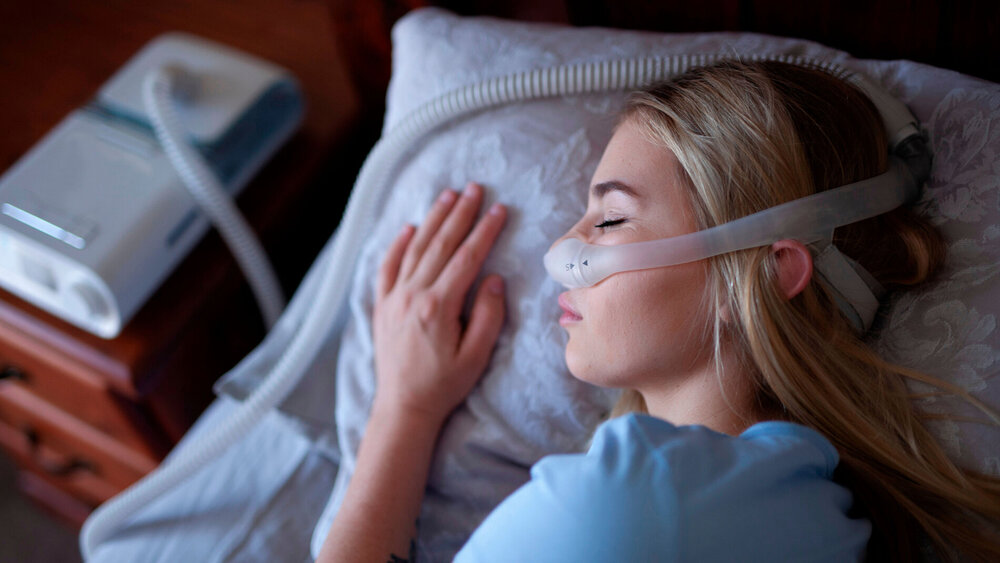 Junge Frau schläft mit CPAP-Maschine