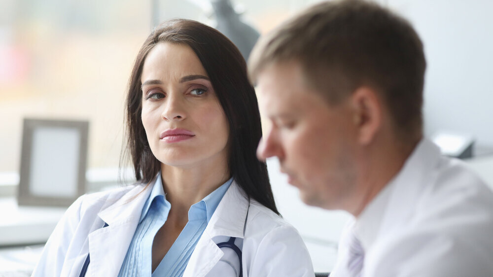 Woman dissatisfied doctor distrust looks at her colleague portrait. Incorrect treatment concept