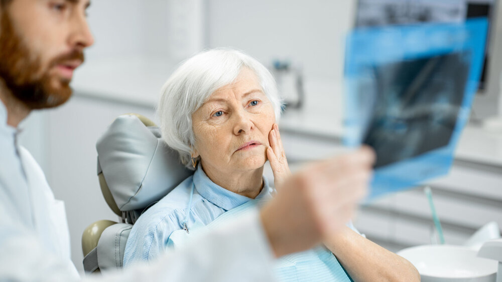 Zahnarzt bespricht Röntgenbild mit älterer Patientin