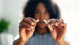 Close-up of woman breaking down cigarette to pieces. Quit smoking concept