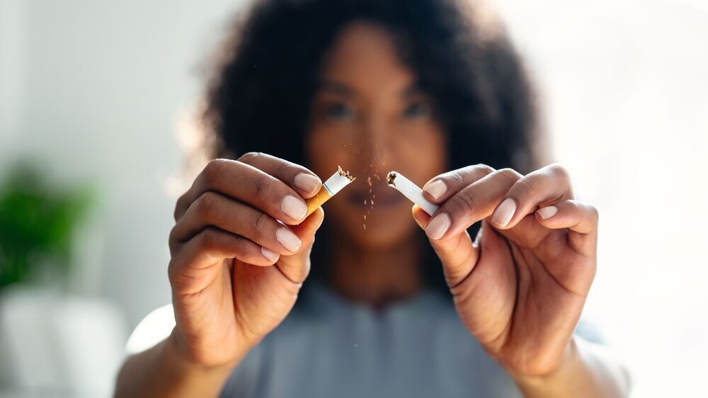 Close-up of woman breaking down cigarette to pieces. Quit smoking concept