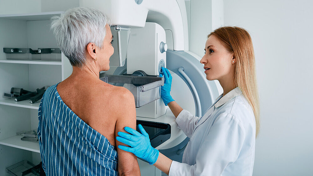 Senior woman having mammography scan at hospital with medical technician. Mammography procedure, breast cancer prevention