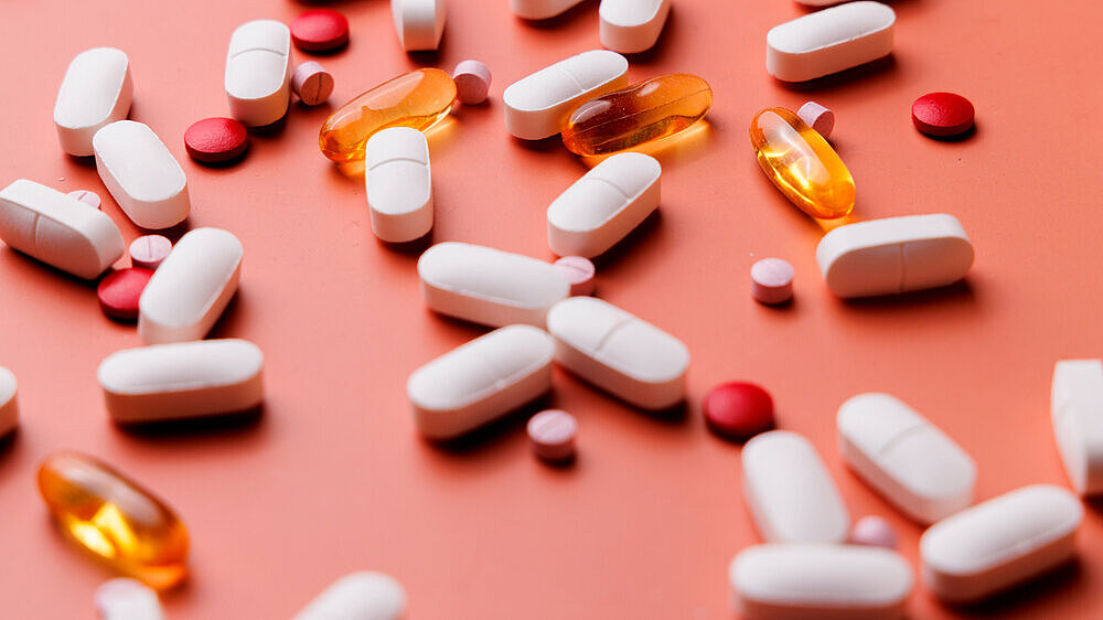 Scattered medical pills of various sizes and colors on a cream gradient background for clinical treatment and health supplement ads. Collection of colorful pills and tablets on a soft cream background. Great for representing medication management, pharmacy and pharmaceutical shots.