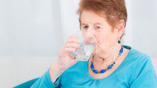 Seniorin trinkt ein Glas Wasser