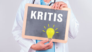 Ärztin mit einer Tafel auf der KRITIS steht und einer leuchtenden Lampe