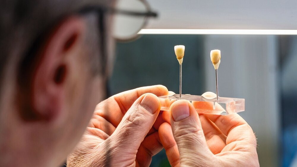 Dentaltechniker begutachtet Zahnersatz