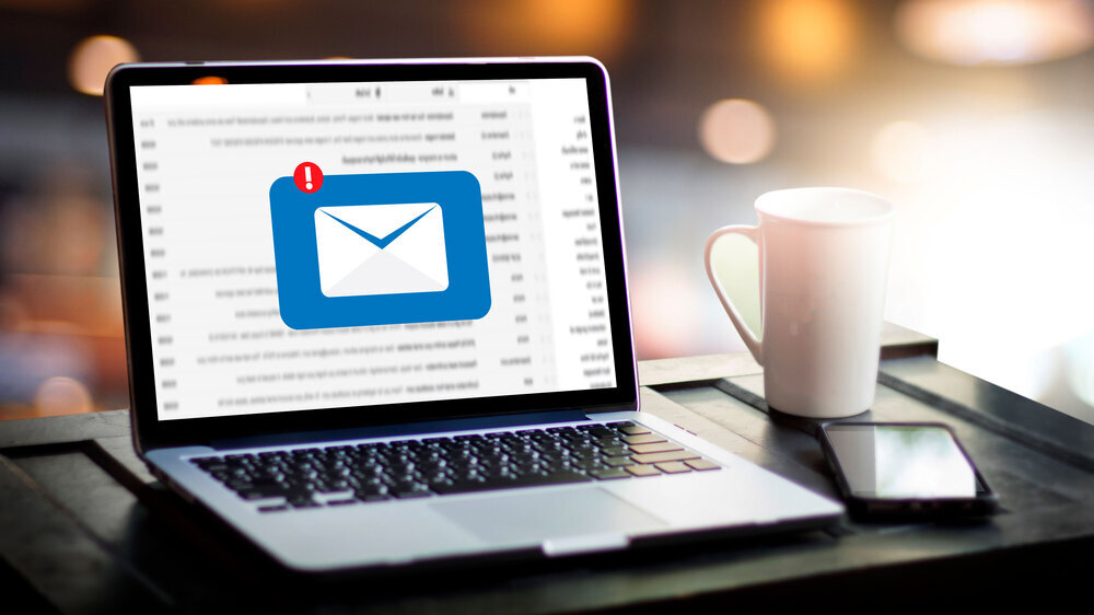 Laptop mit geöffnetem Display zeigt Warnung vor möglicher Fake-Mail an. Laptop mit geöffnetem Display zeigt Warnung vor möglicher Fake-Mail an.