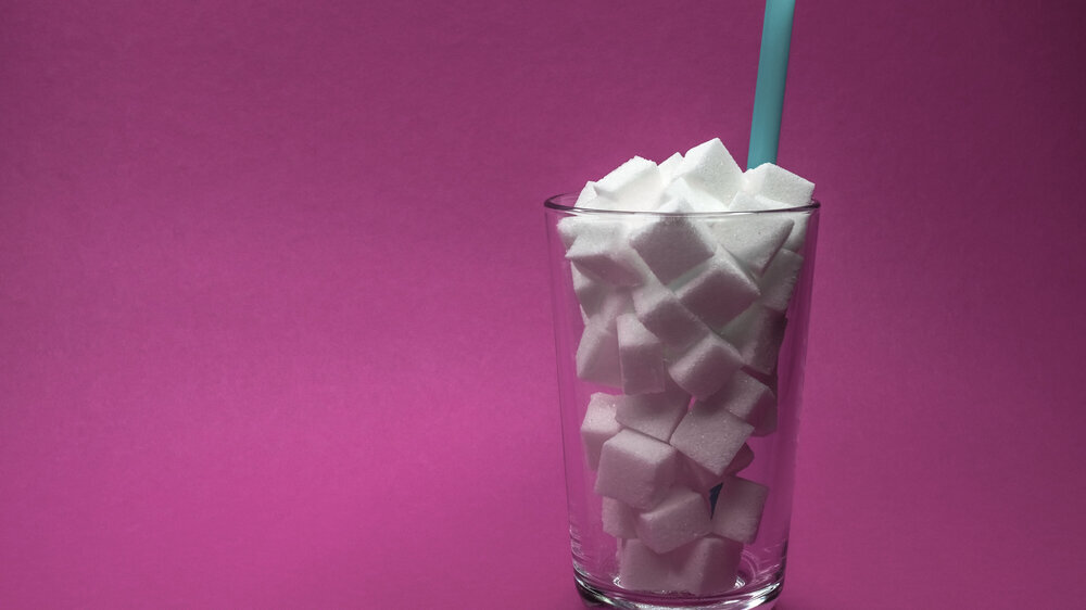 Themenfoto: Glas voll Zuckerwürfel mit Strohhalm