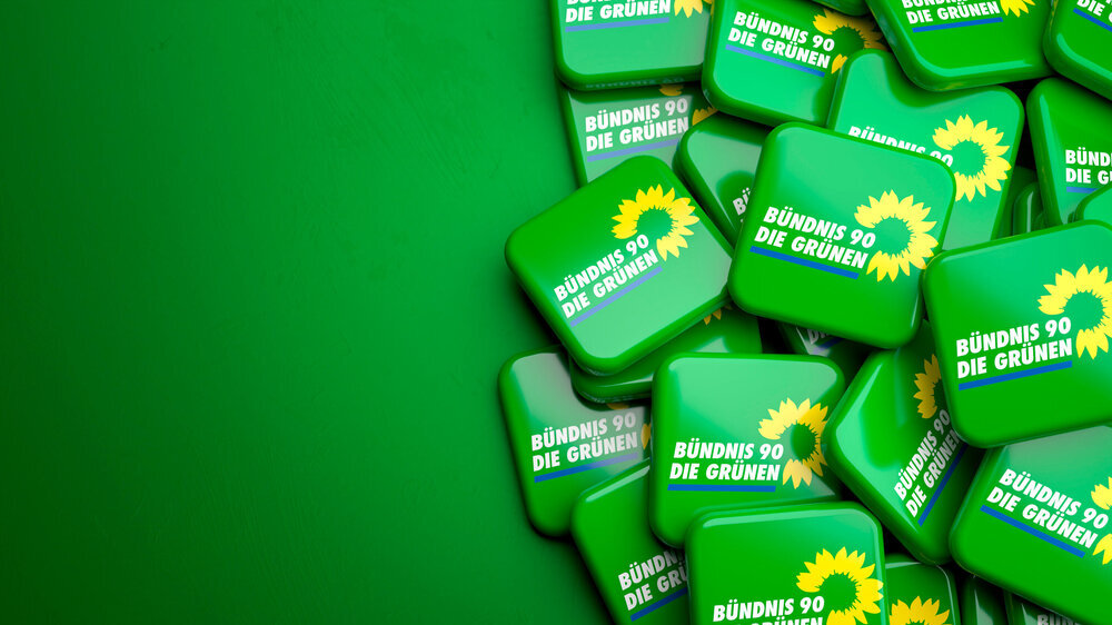 Logo Bündnis 90 / Die Grünen liegt auf einem grünen Hintergrund Ein Haufen von Buttons mit dem Logo von Bündnis 90/Die Grünen liegt auf einem grünen Hintergrund