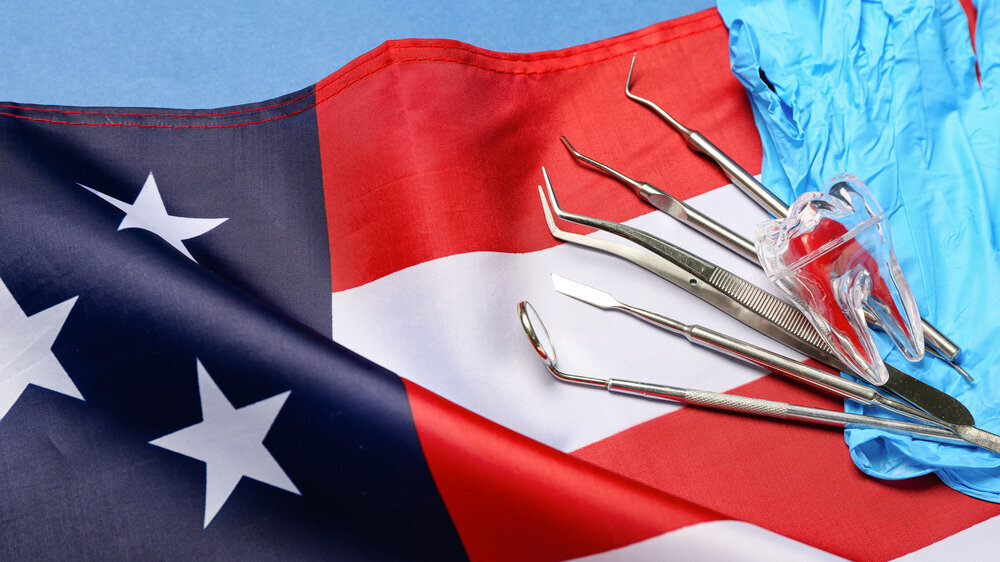 Dental tools with gloves and USA flag on blue background, closeup Zahnmedizin in den USA