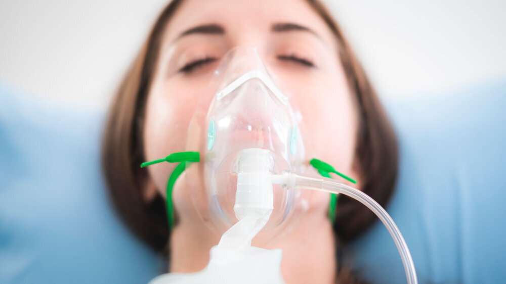 woman patient wearing oxygen mask sleeping on hospital bed, Pre oxygenation for general anesthesia. Surgery equipment Frau in Vollnarkose Anästhesie