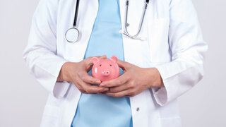 Arzt mit einem Sparschwein in den Händen