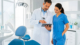 Zahnarzt und Zahnmedizinische Fachangestellte beraten zu Patientenfall in der Praxis.