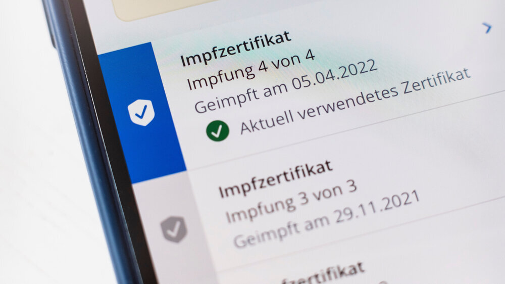 Impfzertifikat für 4. Impfung auf einem Handy Display Impfzertifikat für 4. Impfung auf einem Handy Display