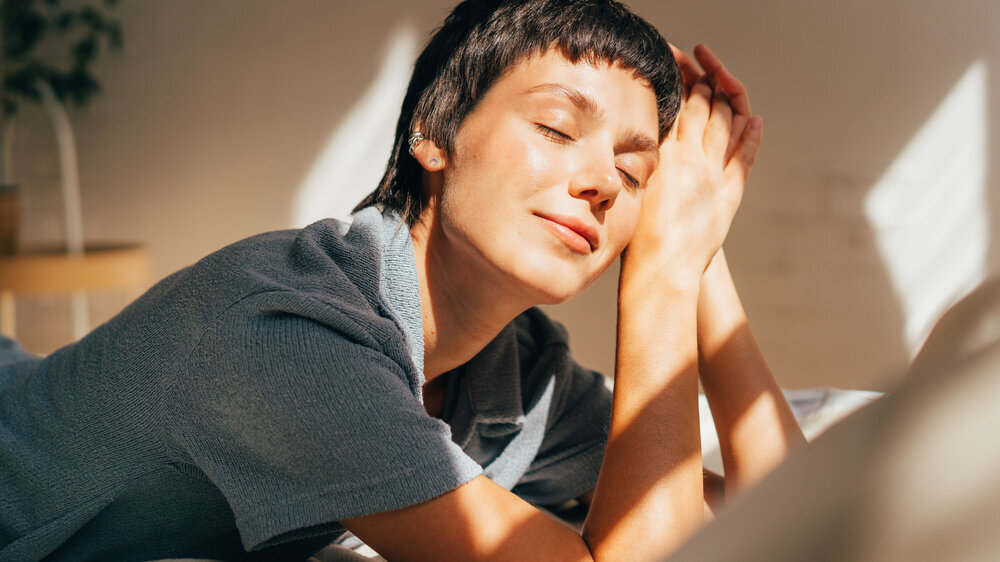 A woman lies on a bed in bright sunlight from the window. A woman lies on a bed in bright sunlight from the window.