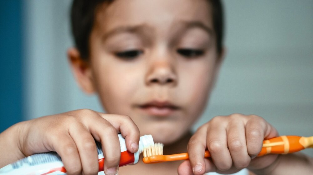 selective focus of diligent boy applying toothpaste on toothbrush