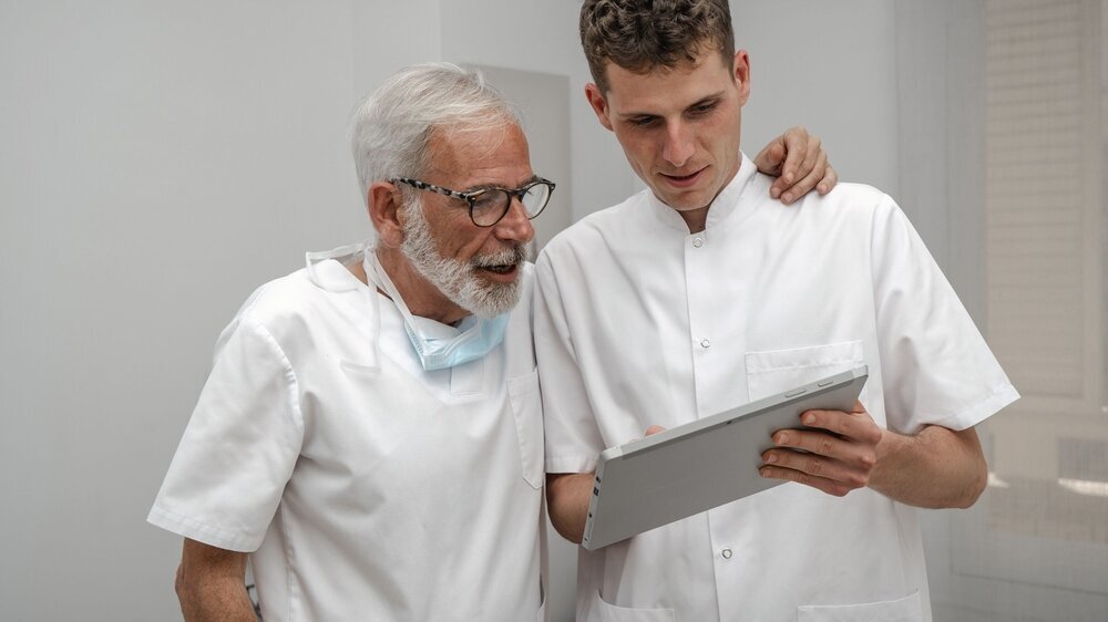 älterer Zahnarzt diskutiert mit jungem Kollegen