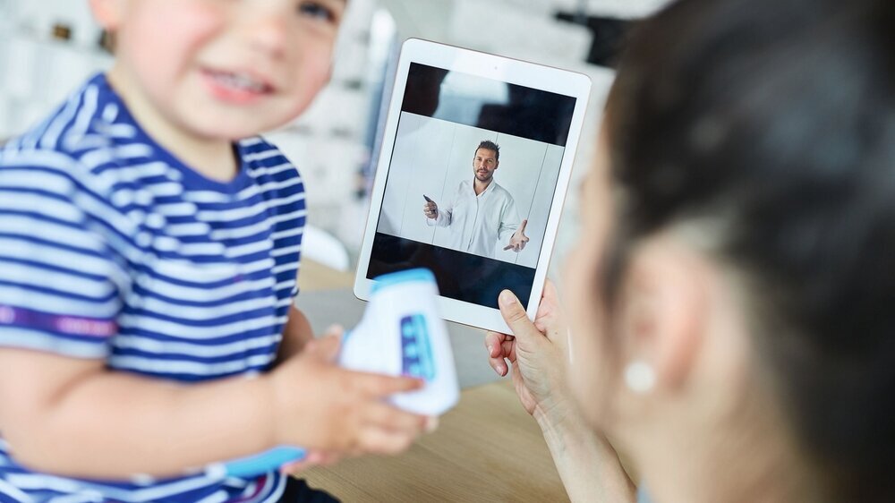 Mutter mit Kind im Videochat mit einem Kinderarzt Mutter mit Kind im Videochat mit einem Kinderarzt
