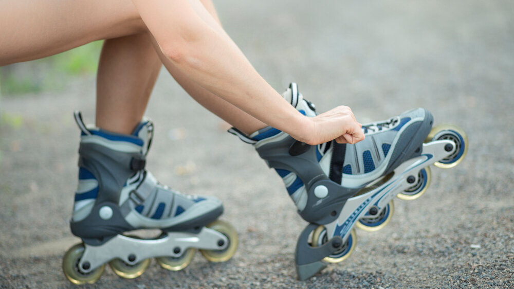 Junge Frau zieht sich Inlineskater an Junge Frau zieht sich Inlineskater an