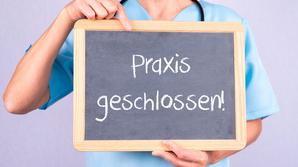 Ärztin mit einer Tafel auf der Praxis geschlossen steht. Ärztin mit einer Tafel auf der Praxis geschlossen steht.