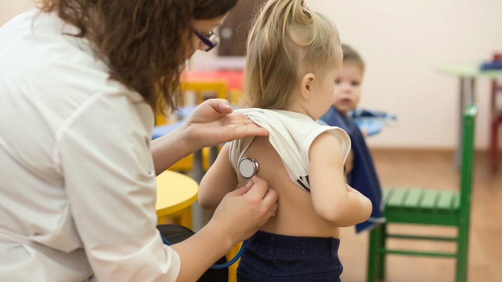 Ärztin untersucht Kind im Kindergarten.