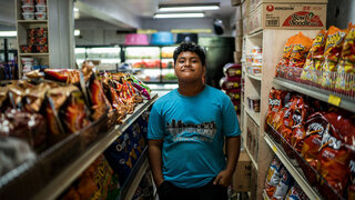 On 21 August 2023 in Pohnpei, Federated States of Micronesia, G'okie Samuel, 14, poses for a portrait in a grocery store he frequents in downtown Kolonia. The shop sells mostly imported goods from the western Pacific.

The Micronesian island of Pohnpei is home to more than 30,000 people. Despite being surrounded by rich waters and lush greenery, the island's food environment has become saturated with processed imports from both sides of the Pacific Ocean, sidelining traditional root crops and sea produce.

For lunch at Pohnpei Island Central School, students can choose between healthier offerings such as dishes with rice and meat, sandwiches and fruit, or less nutritious options like instant noodles, sugary snacks and drinks.

G’okie says, “At my school, we have a place where we buy our food and drinks. My family has told me not to buy crackers and soda because it’s not good for my body.”

Gloria, the school’s shop owner, states, “My bestseller is my brownies. What I noticed is the students like the processed food versus our local healthy goods. I think that we are so programmed in just going to a store and it's fast and easy and tastes good. Not thinking about if it's really good for you.”

Cromwell Bacareza, Chief of the UNICEF office in Micronesia, describes the issue of overweight and obesity in the country: “In Micronesia, more than 50% of children and adolescents are [living with] obesity. A lot of children now are consuming more processed food, and what's available and more convenient are those processed foods that they can actually buy immediately. Rather than going to healthy snacks or vegetables and fruits, there is an increasing demand for ramen, candies and soda. The schools contribute significantly, especially when children, what they eat and what they learn in schools, they bring that habit or that learning to the community. If what they learn in school is eating sugary food or sugary drinks, then we are facing a danger of having a vicious cycle. A school has to be a healthy environment for children to be able to thrive.” 

UNICEF is advocating for a school policy that only allows healthy food to be sold in schools, and many schools are working hard to keep their canteens free of ultra-processed foods.

G’okie typically eats healthier foods at home than he does at school. He says, “What I tend to have in the evenings is rice and fish. We also add breadfruit to the basket. I believe the reason why I eat fruits and vegetables is because it's good for your body and it will keep you healthy.” G’okie also likes the thrill of climbing trees near his house to pick fruit.

Cromwell notes, “In Micronesia, there is an abundance of fruits and vegetables: papaya, pineapple, guyabano, avocado. We need to advocate more for people to make use of this. They can continue eating ramen but they can also infuse some vegetables in there that is available locally.”

Leilani, G’okie’s grandmother, thinks back on how much simpler nutrition was when most of the options were locally grown – often self-grown – staples, before advertising took hold and influenced young minds making decisions about which foods to consume. “Before, no chocolate, no branding, nothing. Only local. We raise and grow, we eat.”