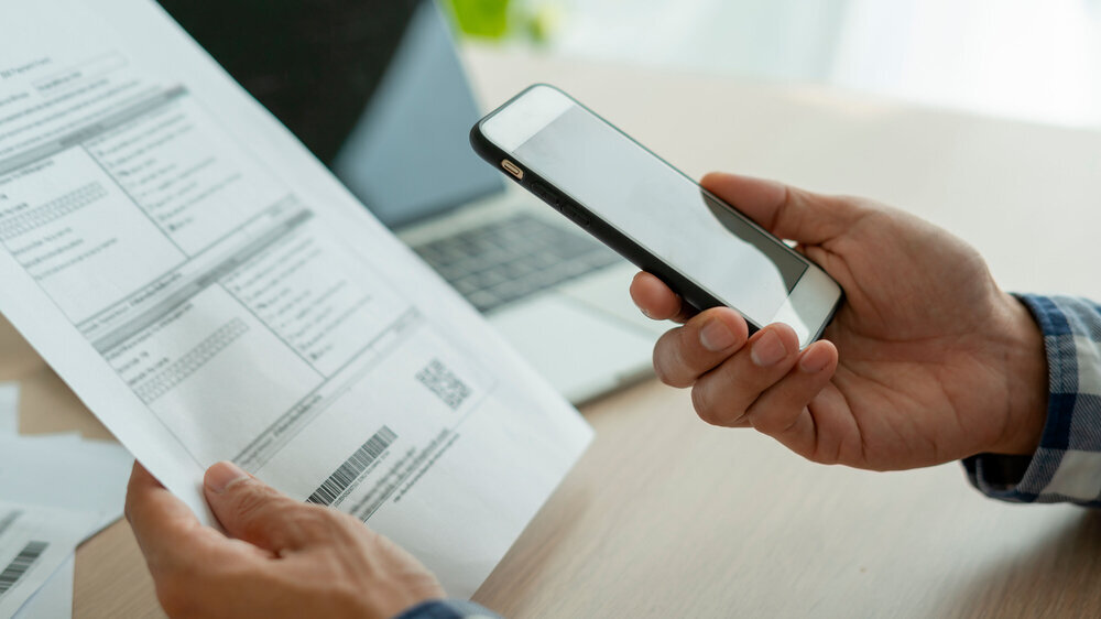 business man use phone to scan barcode or QR codes to pay credit card bill after receiving document invoice online. payment, receive, paying electricity, digital payments without money, technology Gehaltsabrechnung