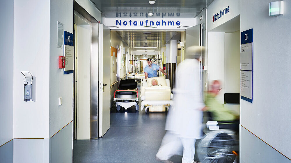 Notaufnahme Krankenhaus Arzt Rollstuhl Patient Eingang Notaufnahme Eingang Krankenhaus mit Arzt Rollstuhl und Patient in Bewegungsunschärfe auf dem Flur und Pfleger mit Krankenbett