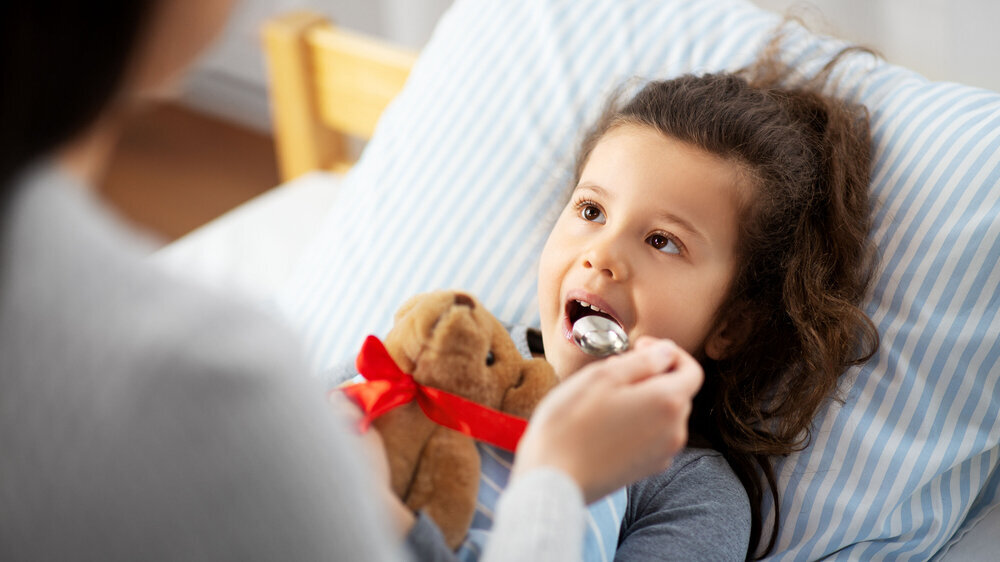 Mutter gibt kranker kleiner Tochter Fiebersaft Mutter gibt kranker kleiner Tochter Fiebersaft
