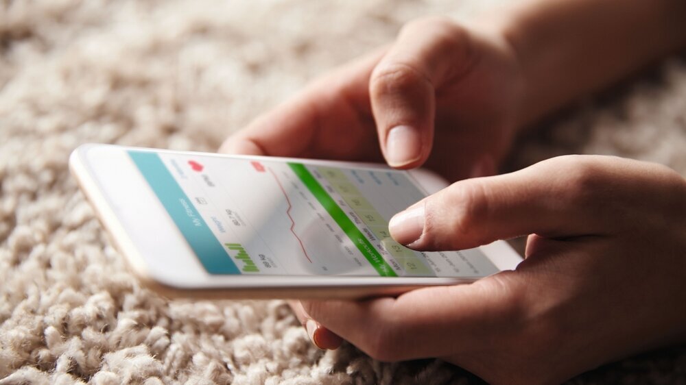 Close up of hands holding a smartphone on fitness app Gesundheits-App