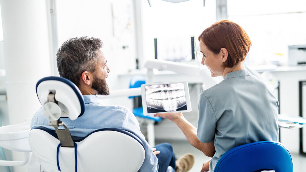 Rückansicht eines Patienten und einer Zahnärztin in Zahnarztpraxis. Rückansicht eines Patienten und einer Zahnärztin in Zahnarztpraxis.
