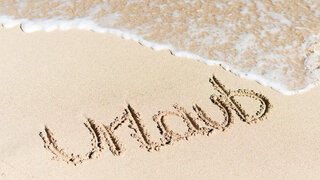 Urlaub als Schriftzug im Sand am Strand.
