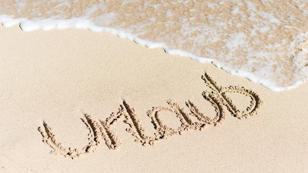Urlaub als Schriftzug im Sand am Strand.
