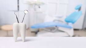 Oral dental hygiene. Healthy white tooth and dentist mirror with explorer probe instrument against blurred dentist Office background with dental chair.