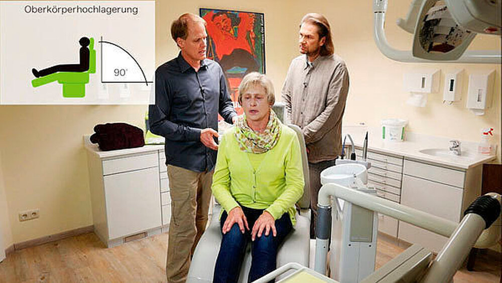 Kapitel 8: kardialer Notfall: Diese Patientin klagt über Schmerzen im Brustkorb und im linken Arm. Die Patientin aufrecht lagern, also den Behandlungsstuhl im rechten Winkel aufstellen. Pahl erklärt, warum es so wichtig ist, den Patienten zu beruhigen. Sollte der Patient kein Herzpatient sein und kein eigenes Notfallspray dabei haben, reichen zwei Hübe Nitroglyzerin-Spray auf die Zunge als Erstmaßnahme. |