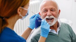 Zahnärztin beim Check-up eines älteren Patienten