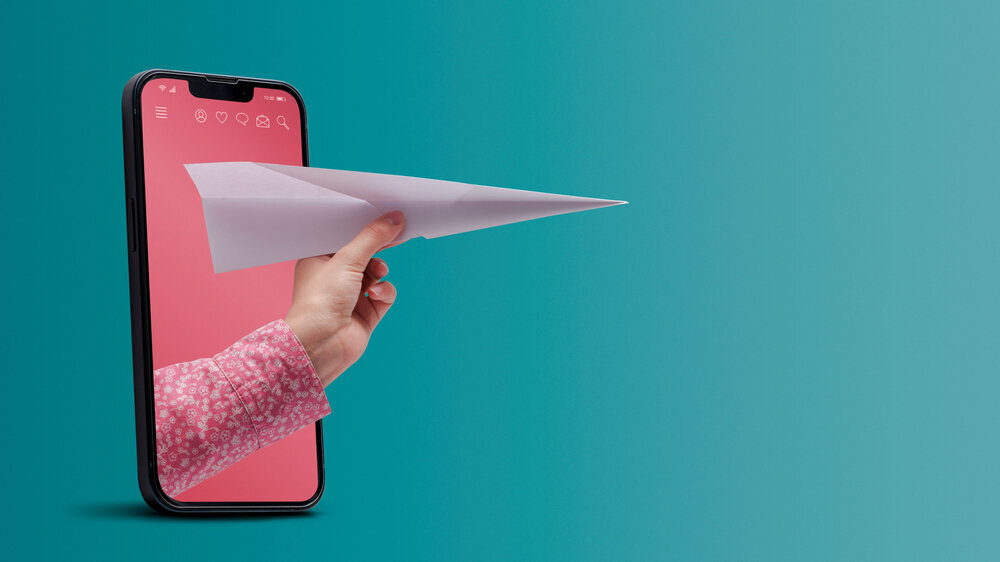 Hand holding a paper plane in a smartphone Hand mit Papierflieger
