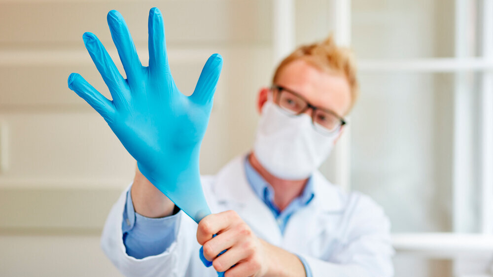 Arzt zieht sich Handschuhe an Arzt zieht sich Handschuhe als Arbeitsschutz für die Hygiene an