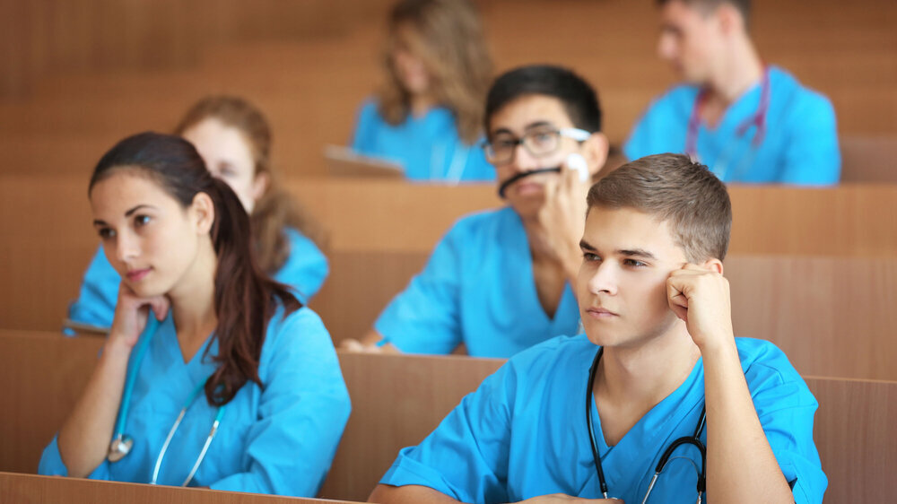 Medizinstudierende sitzen im Hörsaal einer Universität und überlegen, folgen dem Unterricht.