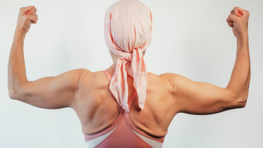 Woman with pink headscarf, view from behind, cancer awareness. Krebspatientin