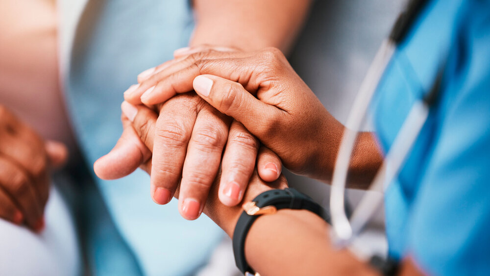 Pflegepersonal hält die Hand einer Patientin