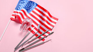 Dental tools with plastic tooth and USA flag on pink background