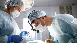 Dental surgery. The surgeon and the assistant. The patient is unrecognizable. Modern dentistry. Photo in the operating room. Concept of healthcare.
