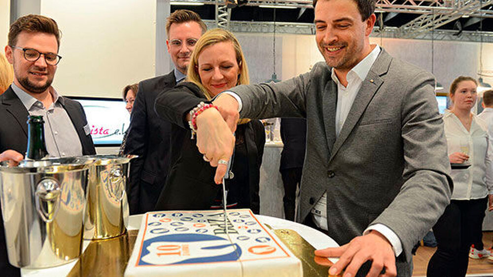 10 Jahre Bundesverband der zahnmedizinischen Alumni in Deutschland: Der BdZA-Vorsitzende Ingmar Dobberstein und Kassenwart Juliane von Hoyningen-Huene schneiden auf der IDS die Geburtstagstorte an.
